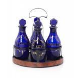 AN REGENCY JAPANNED TIN CRUET FRAME AND FIVE CONTEMPORARY BLUE GLASS CONDIMENT BOTTLES AND STOPPERS,