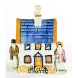A PRATTWARE BANK IN THE FORM OF A HOUSE FLANKED BY FIGURES OF A MAN AND WOMAN, 13CM H, CIRCA 1840