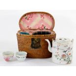 A CANTON FAMILLE ROSE PORCELAIN TEA KETTLE AND COVER AND TWO SIMILAR TEA BOWLS IN FITTED WICKER