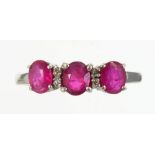 A RUBY THREE STONE RING, THE THREE EVENLY SIZED RUBIES DIVIDED BY PAIRS OF SMALLER DIAMONDS, IN