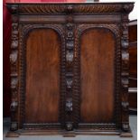 A FLEMISH CARVED OAK BOOKCASE, ENCLOSED BY A PAIR OF ARCHED PANEL DOORS FLANKED BY GROTESQUES AND