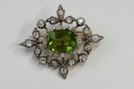 An Edwardian diamond and peridot brooch pendant, the step cut peridot, 13.5 mm by 10 mm by 6.