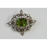 An Edwardian diamond and peridot brooch pendant, the step cut peridot, 13.5 mm by 10 mm by 6.