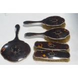 A silver tortoiseshell pique mounted five piece dressing table set, each of shaped outline,