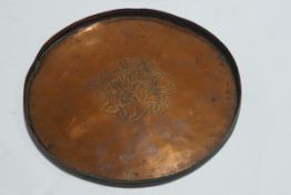 A small circular copper tray by Hugh or Brian Wallis, engraved with flowers,
