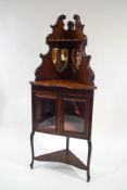 An Edwardian mahogany corner cabinet with raised mirrored back,