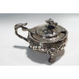 A Victorian silver cauldron shaped mustard pot embossed in high relief with flowers and leaf