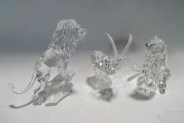 Three Swarovski Crystal animals: Lion on a rock, Seated Leopard (one eye missing) and an Ibex,