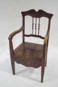 An Edwardian beech commode armchair with carved cresting rail and turned spindles