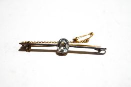 A 15ct gold bar brooch, set with an oval cut pale blue stone,