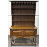 An early 20th century oak dresser with raised plate rack above two panelled doors with decorative