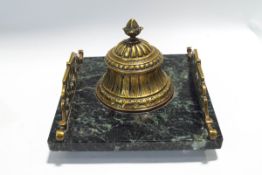 A Victorian brass inkwell on a green variegated marble base,