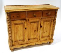 A 19th century Continental pine dresser base with three drawers above two panelled doors on turned