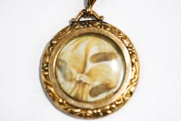 A mourning locket, tagged '9ct', circa 1900, the glazed front containing a hair arrangement,