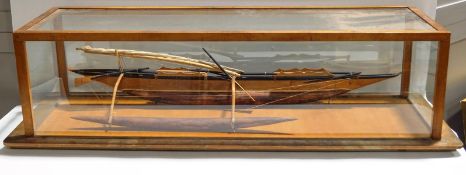 A model of a Polynesian boat in a glass case,