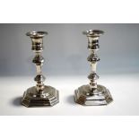 A pair of silver plated candlesticks, in the Georgian style, with square cut corner sunken bases,