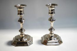 A pair of silver plated candlesticks, in the Georgian style, with square cut corner sunken bases,