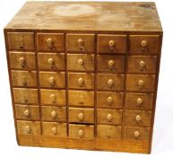 An oak index card filing cabinet with thirty drawers with turned handles (some missing) 76cm high x