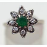 A diamond and emerald flower head cluster ring, the white mount stamped '18ct',