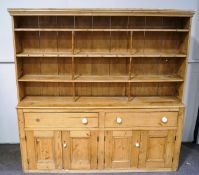 A late Victorian pine dresser with raised plate rack above two deep drawers above four panelled