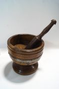 A large rustic wood pestle and mortar, metal bound with carved triangular detail,