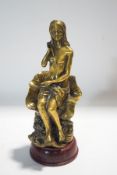 A brass figure of a seated semi-nude maiden, on a turned wooden base,