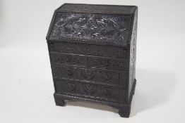 A late 19th century stained oak bureau, heavily carved in the Jacobean style,