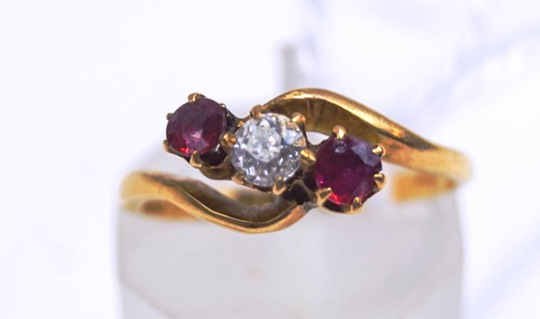 An 18 carat gold three stone diamond and ruby cross over ring, London 1916,