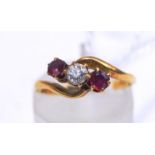 An 18 carat gold three stone diamond and ruby cross over ring, London 1916,