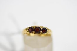 A three stone garnet ring, stamped '18ct', finger size K, 3.