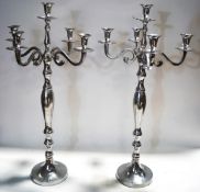 A large pair of metal four branch candelabra, on baluster supports and flared bases,