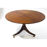 A Regency mahogany breakfast table on outswept legs with brass mounts,