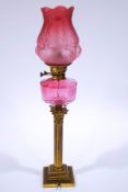 A Victorian brass oil lamp, with engraved cranberry glass shade and reservoir,