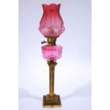 A Victorian brass oil lamp, with engraved cranberry glass shade and reservoir,