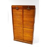 A 20th century double tambour fronted cabinet, with replacement shelves,