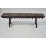 An oak bench, with carved sides, upon trestle style legs, constructed from old timbers,