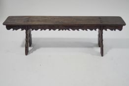An oak bench, with carved sides, upon trestle style legs, constructed from old timbers,