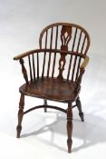 A 19th century elm Windsor armchair, with turned legs joined by a crinoline stretcher,