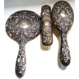 A silver three piece dressing table set with embossed silver mounts, comprising a hand mirror,