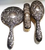 A silver three piece dressing table set with embossed silver mounts, comprising a hand mirror,