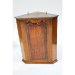 A 19th century oak hanging corner cabinet, the interior fitted with two shaped shelves,