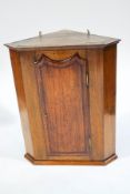 A 19th century oak hanging corner cabinet, the interior fitted with two shaped shelves,