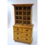 An early 20th century pine chest with two glazed doors above two short and two long drawers,