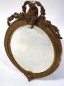 A late 19th century oval mirror with gesso frame, surmounted by a putti with laurel leaf swags,
