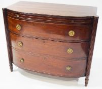 A Regency mahogany bow front chest of drawers, with baize lined brushing slide over three drawers,