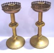 A pair of brass Gothic style candlesticks, with pierced drip pans and flared bases,