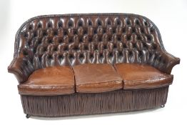 A leather buttonback sofa, with ruched apron and trim,