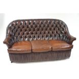 A leather buttonback sofa, with ruched apron and trim,