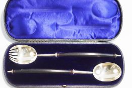 A pair of Victorian silver salad servers, by George Adams, London 1881, with long ebony handles,