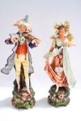 A pair of early 20th century continental ceramic figures of a musician and a lady,
